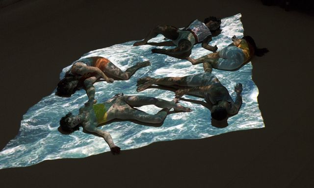Group of performers lying on surface with projection