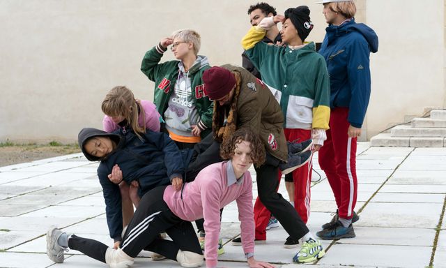 Diverse Gruppe von acht Personen, die zusammen posieren und sich stützen
