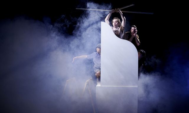 Dancers on a dark stage filled with smoke performing to be on a helicopter