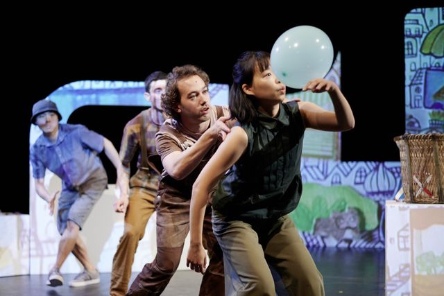 Group of performers balancing a balloon over their bodies