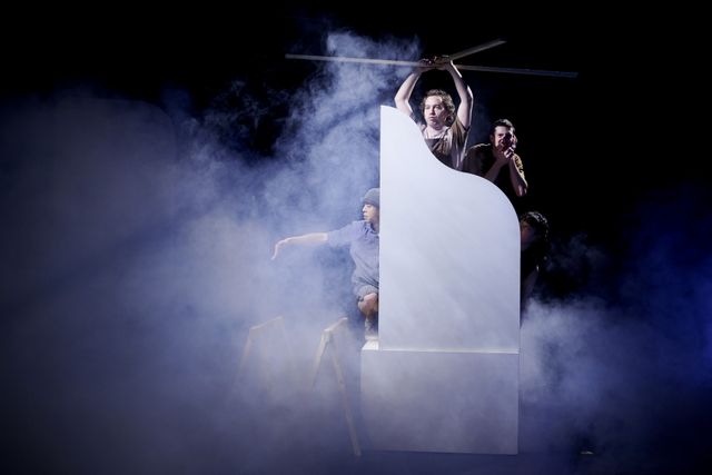 Dancers on a dark stage filled with smoke performing to be on a helicopter