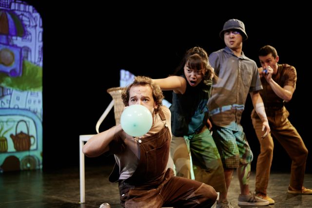 Group of performers building a row, blowing up a balloon