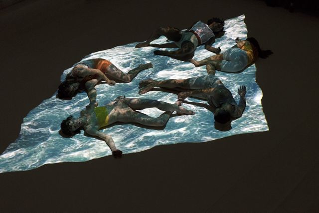 Group of performers lying on surface with projection