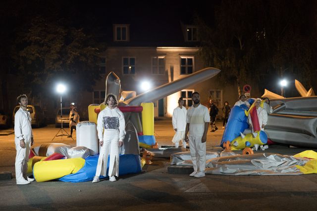 Group of performers dressed in white standing between colorful bouncy castles