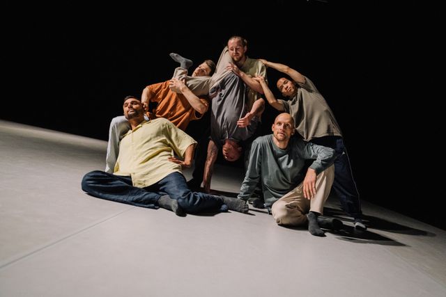 Group of male performers posing together, one of them upside down