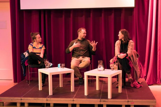 Two women and one man discussing on a small stage