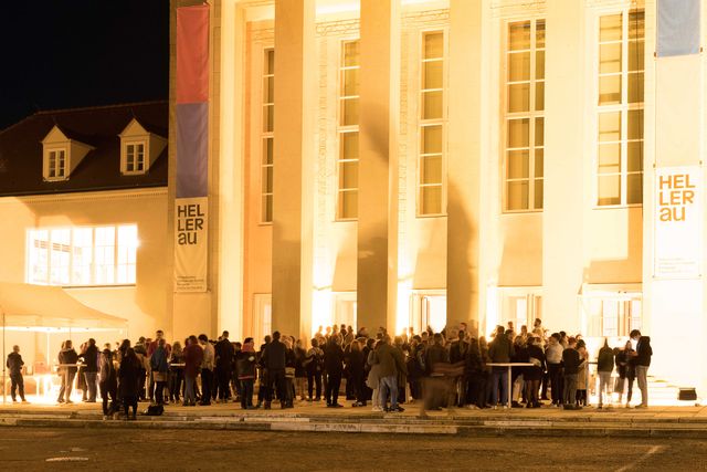 Crowd of people standing in front of brightly lit Festspielhaus Hellerau
